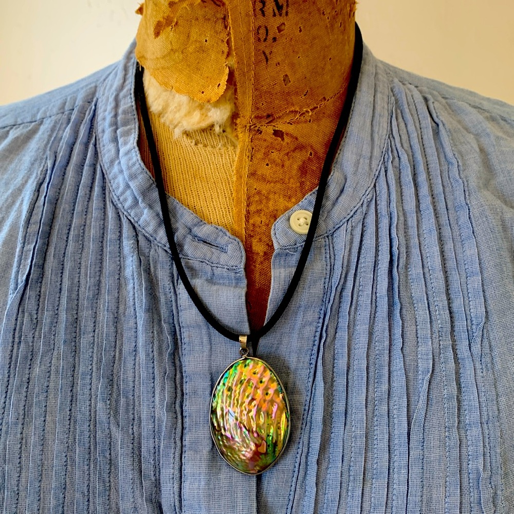 Vintage abalone pendant with silver-toned bezel on black cord.